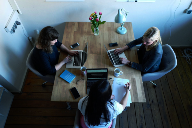 Three women working on laptops at a table for Version 1 SPSS Training